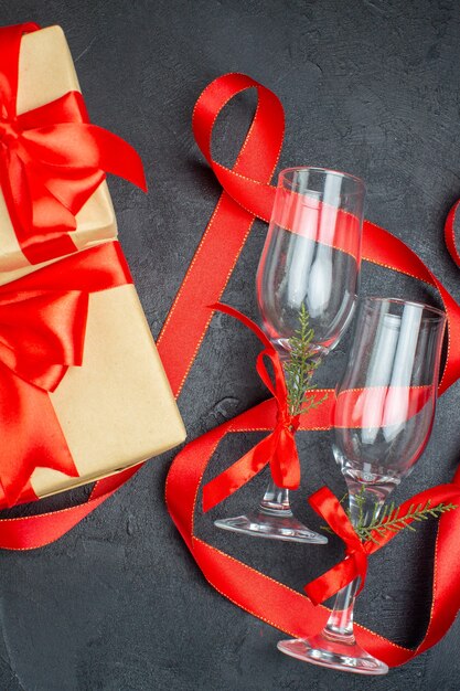 Half shot of beautiful gifts and glass goblets on dark background