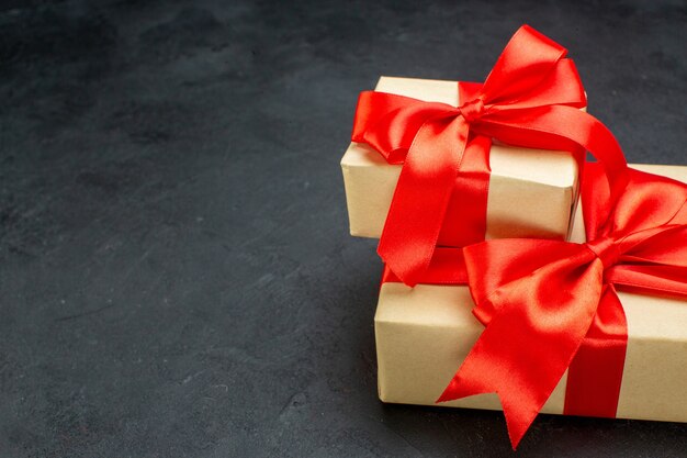 Half shot of beautiful gifts with red ribbon on dark background in horizontal view