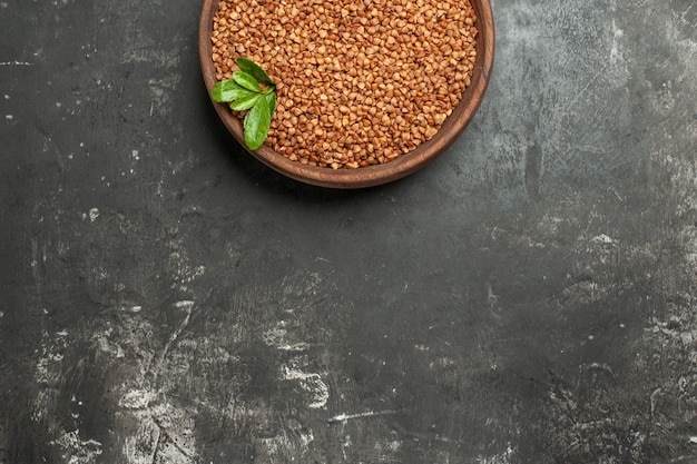 Half shot of buckwheat groats with green in a brown bowl on gray table