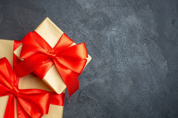 暗い背景の右側に弓形のリボンと美しい贈り物とクリスマスの背景のハーフショット