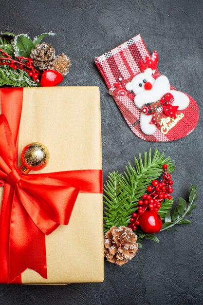 Half shot of Christmas mood with beautiful gifts with bow-shaped ribbon and fir branches decoration accessories xsmas sock on a dark background vertical view