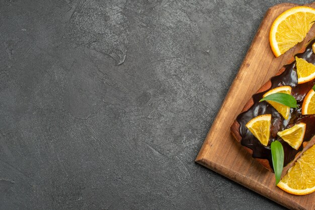 Half shot of delicious cakes decorated with lemon and chocolate on cutting board on black table