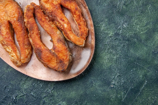 Half shot of delicious fried fish on a brown plate on mix colors table with free space