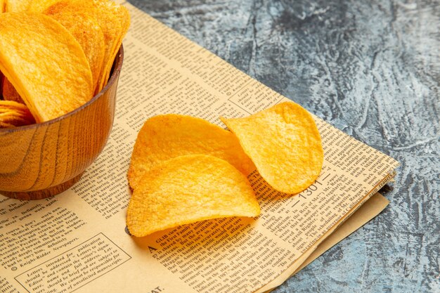 Half shot of delicious homemade chips on newspaper on gray table