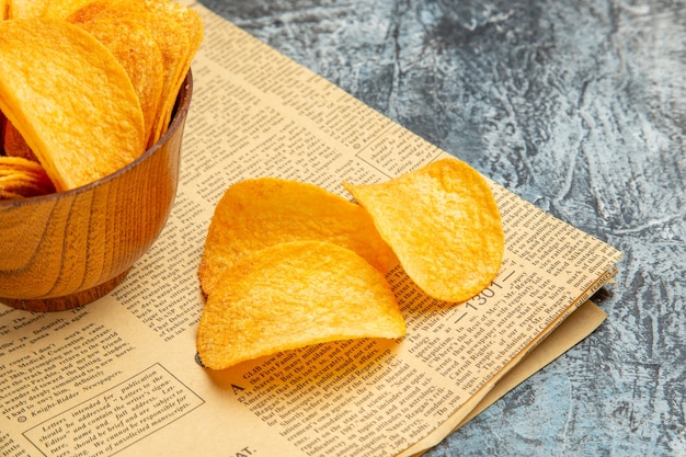 Half shot of delicious homemade chips on newspaper on gray table