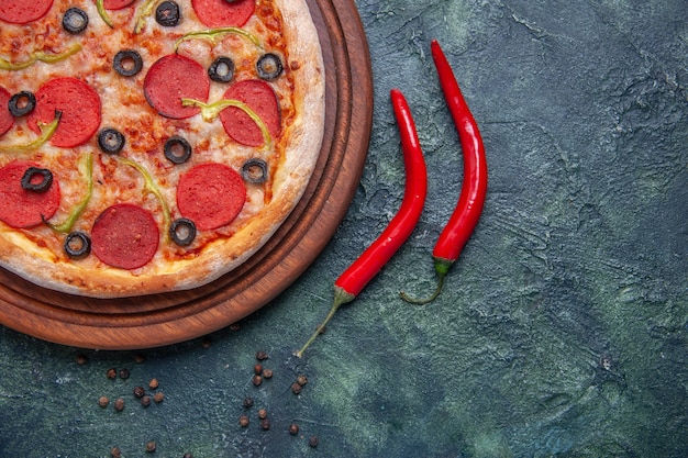 여유 공간이있는 격리 된 어두운 표면에 나무 커팅 보드와 붉은 고추에 맛있는 피자의 절반 샷