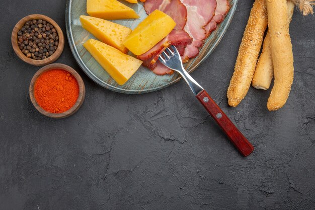 Half shot of delicious sausage and cheese slice on a blue plate peppers on a dark background