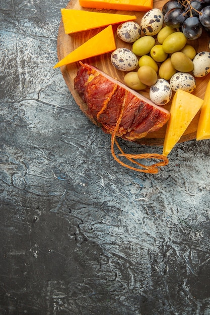 Half shot of delicious snack including fruits and foods for wine on a brown tray on gray background