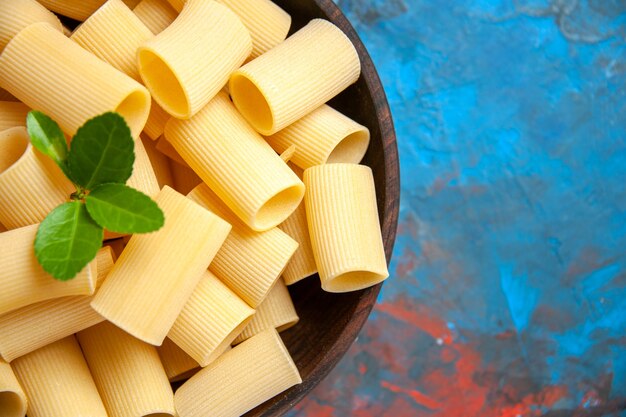 Half shot of dinner preparation with pasta noodles with green in a brown pot on blue background