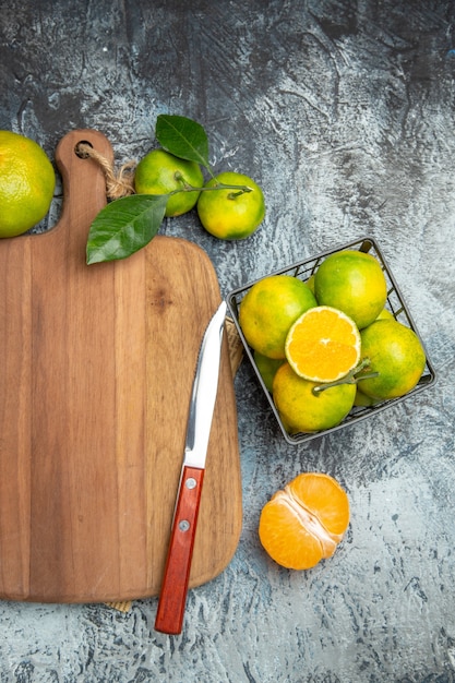 半分の形にカットされた木製のまな板の葉と新聞の灰色のテーブルにナイフで新鮮な柑橘系の果物のハーフショット