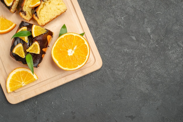 Half shot of fresh orange slices and chopped cake slices on dark table