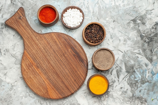 Half shot of healthy wooden cutting board different spices on white table