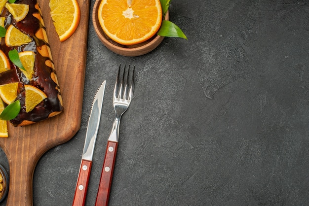 Half shot of soft cakes on board and cut lemons with leaves on dark table