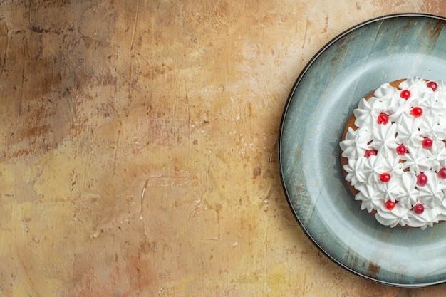 Half shot of tasty cake decorated with cream and currant on a blue plate on the left side on a colorful background