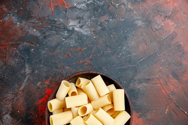 Half shot of uncooked pastas inside the pot on black table 