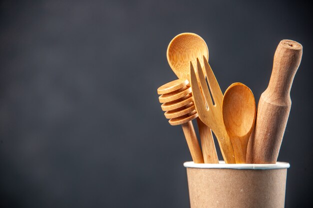 Half shot of wooden sapoons in an empty plastic coffee pot on dark surface