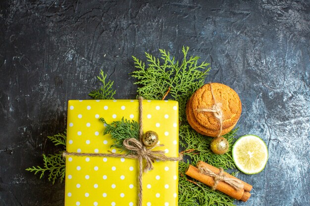 Половина снимка рождественского фона с красивыми желтыми подарочными коробками и сложенным печеньем, лимоном, корицей и лаймом с правой стороны на темном столе