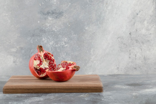 Half sliced fresh pomegranate placed on wooden board.