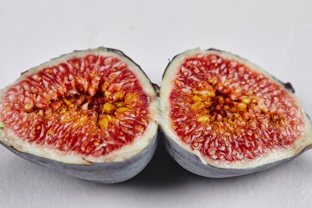 Half slices of ripe fig on white.