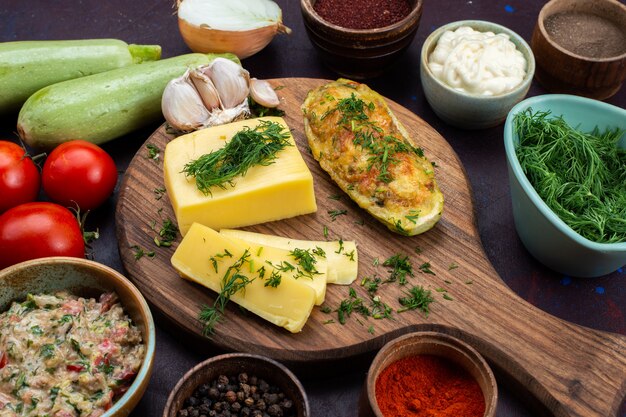 Half-top close view baked squashes with greens cheese seasonings meat and fresh vegetables on dark desk.