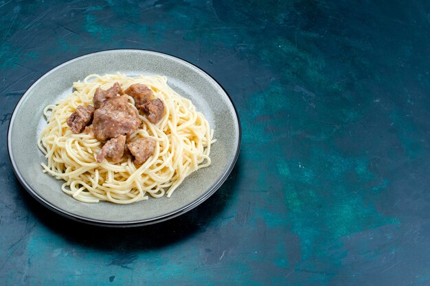 ハーフトップビュー調理済みイタリアンパスタ、青い表面のプレートの内側にスライスした肉パスタイタリア料理食事ディナー生地肉
