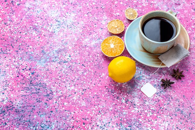 Half-top view cup of tea with lemon on pink desk.