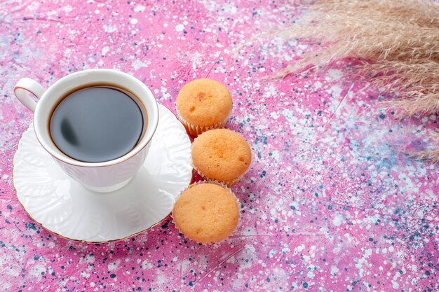 Half-top view of cup of tea with little cakes on the pink surface