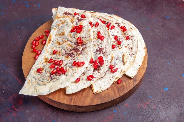 Half-top view delicious meat qutabs pitas with fresh red pomegranates on dark-purple surface meat dough meal pita