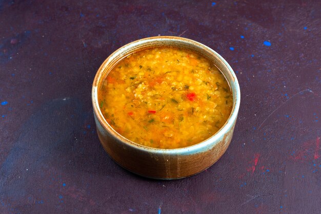Вкусный овощной суп с видом на половину сверху внутри круглой тарелки на темном столе.