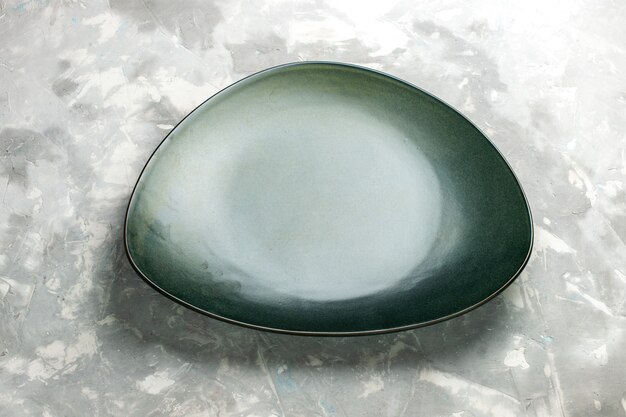 Пустая зеленая тарелка, вид сверху наполовину, изолированная на светло-сером столе.