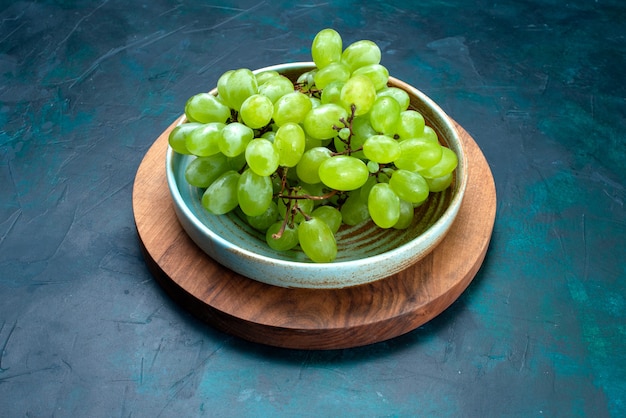 하프 탑보기 신선한 녹색 포도 진한 파란색 책상에 접시 안에 부드러운 육즙 과일.