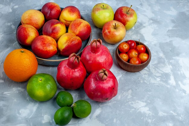 Half-top view fresh peaches delicious summer fruits with tangerines and apple on light-white desk fresh fruits mellow vitamine ripe tree