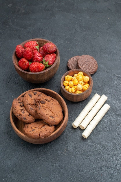 Free photo half-top view fresh red strawberries with sweet biscuits on dark table sugar cookie cake