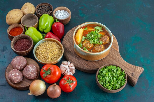 Half-top view fresh vegetables with seasonings meat soup and greens on dark blue desk vegetable food meal dish greens