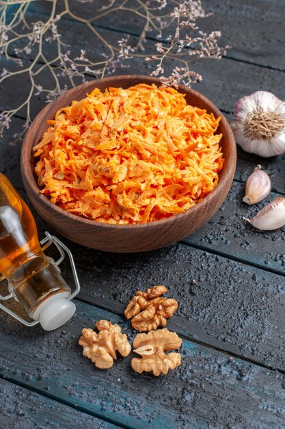 Half-top view grated carrot salad with garlic on dark-blue rustic desk health salad vegetables color diet ripe