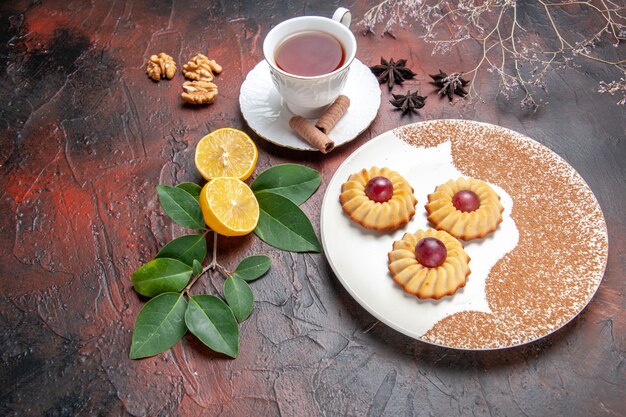 Half-top view little cookies with cup of tea on dark table sugar biscuit cake sweet