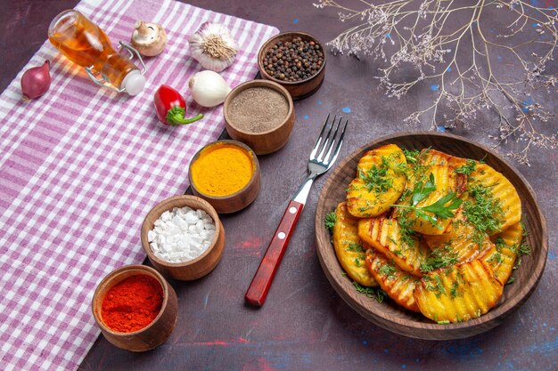 Half-top view tasty cooked potatoes delicious dish with greens and seasonings on dark surface dinner cooking meal potato dish