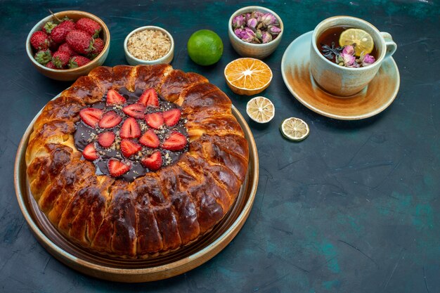 Half-top view of yummy strawberry pie baked delicious cake with cup of tea