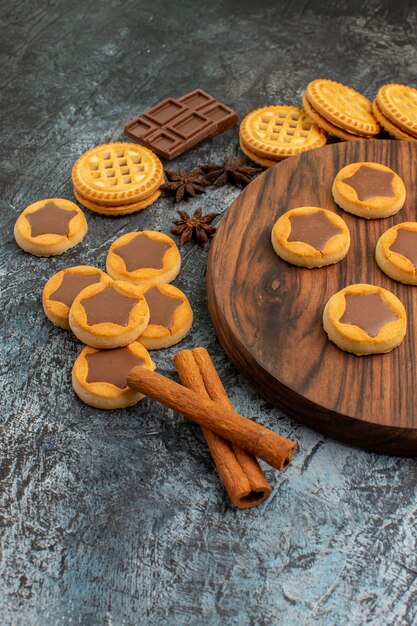 Half view of cookies on wooden platter and cinnamon sticks on grey