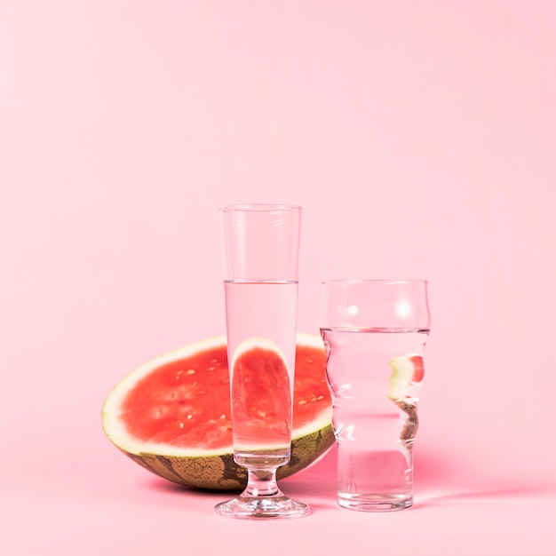 Half of watermelon and glasses with water