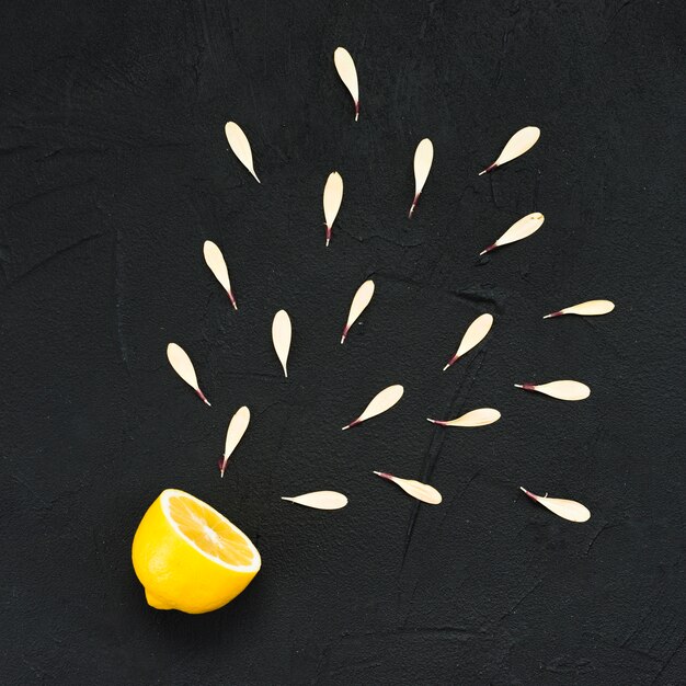 Half of yellow lemon with white petals on black background