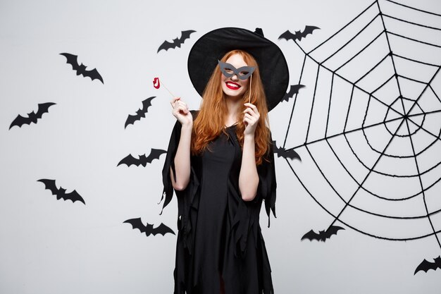 Halloween concept  beautiful girls in black witch dresses holding party props