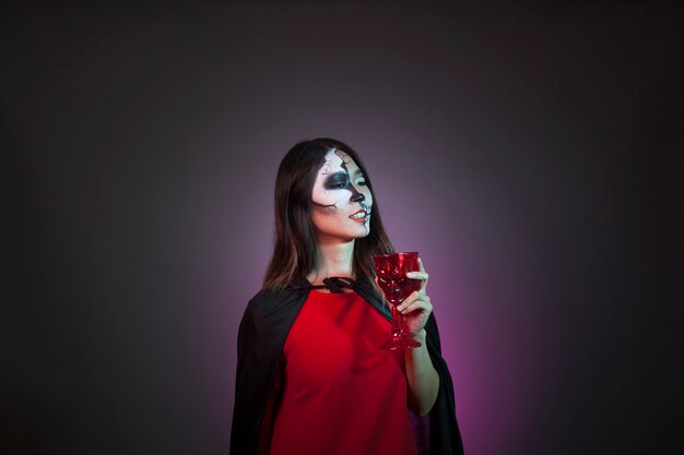 Halloween concept with girl drinking from cup