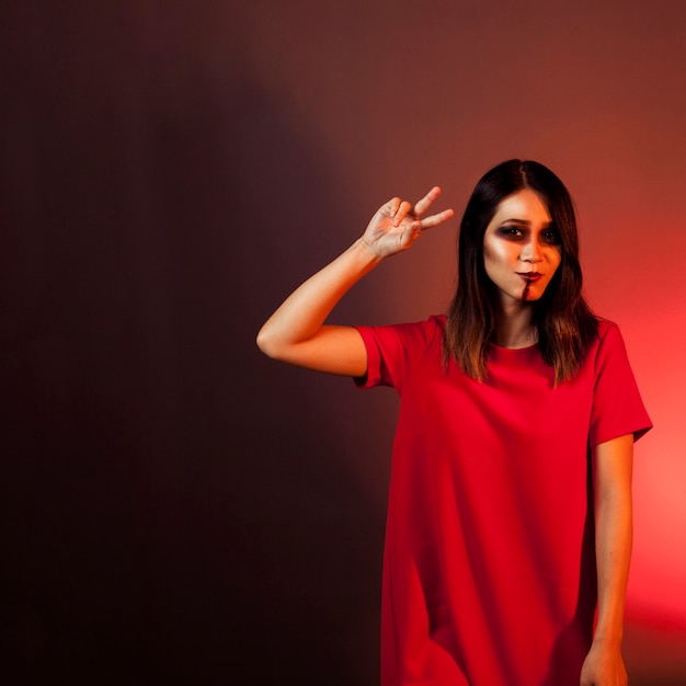 Free photo halloween concept with woman making peace gesture