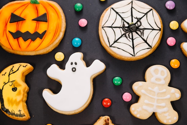 Halloween cookies among candy on black background