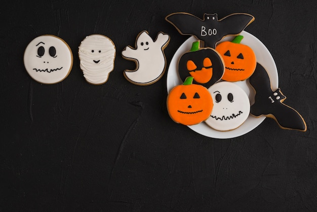 Halloween gingerbread on plate near white cookies 