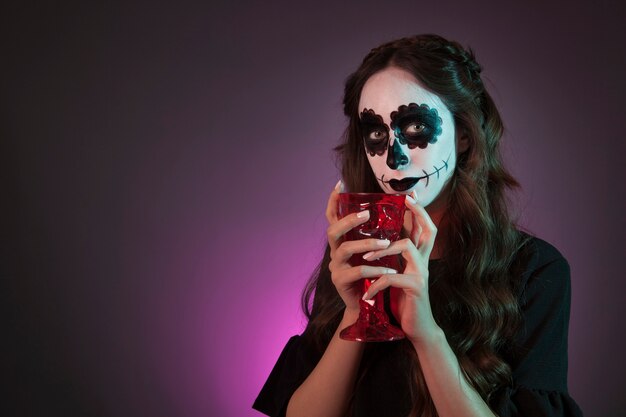 Девушка Хэллоуина, держащая чашку
