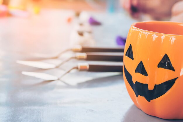 Halloween jack o lantern face mug over blurred boy sculpturing clay toy background