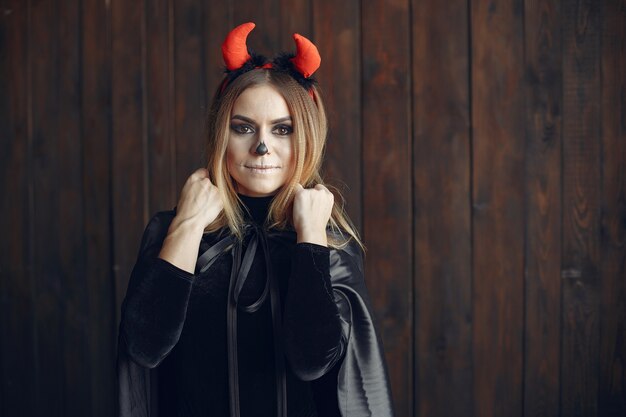 Halloween make-up beautiful woman with blond hairstyle. Model girl in black costume. Halloween theme.