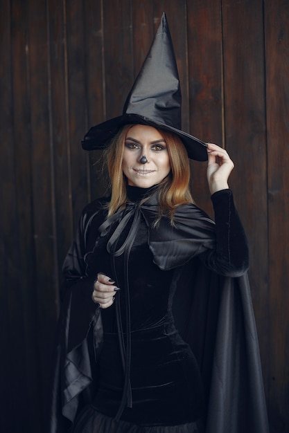 Halloween make-up beautiful woman with blond hairstyle. Model girl in black costume. Halloween theme.